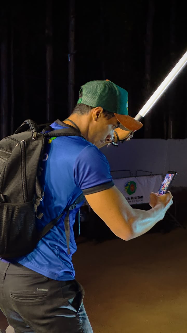 Profissional da CriaArte filmando à noite com celular e bastão de luz LED